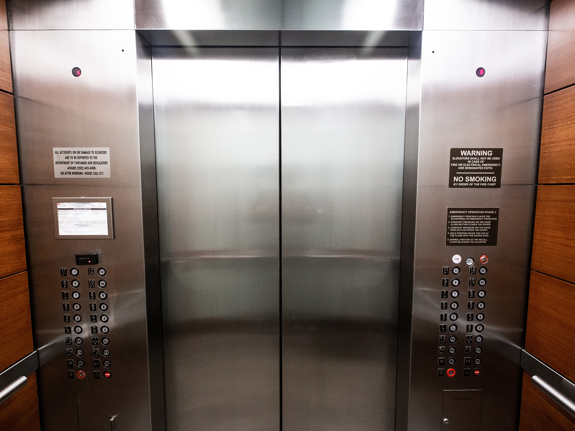 Lift door in the center and all buttons on left and right side of the lift door.