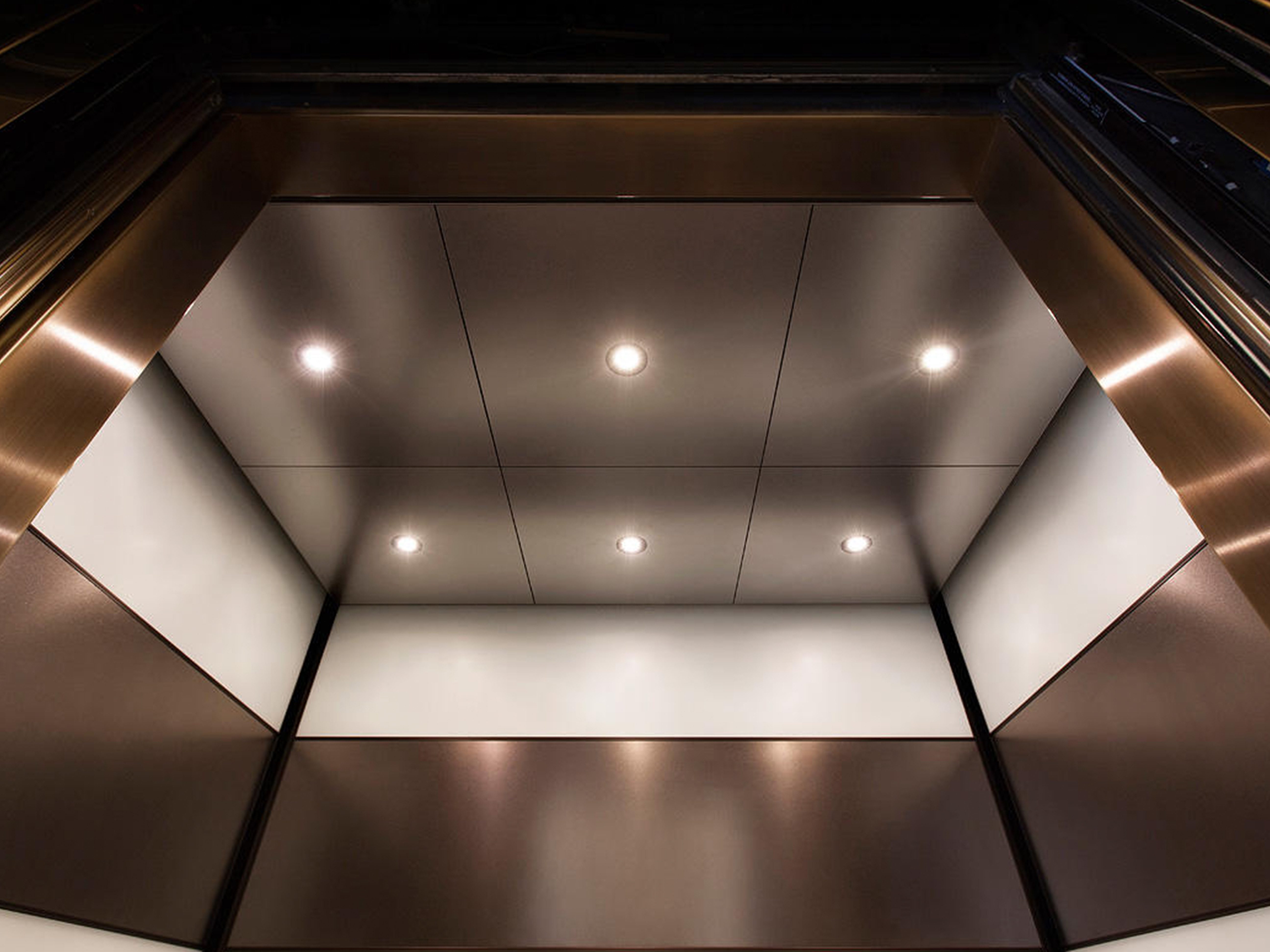 Doors of the Elevator are open and inside Roof of the Elevator can be seen which has circle lights attached.